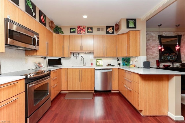 kitchen with sink, appliances with stainless steel finishes, kitchen peninsula, and tasteful backsplash