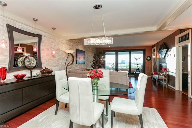 dining room with brick wall, hardwood / wood-style floors, and an inviting chandelier