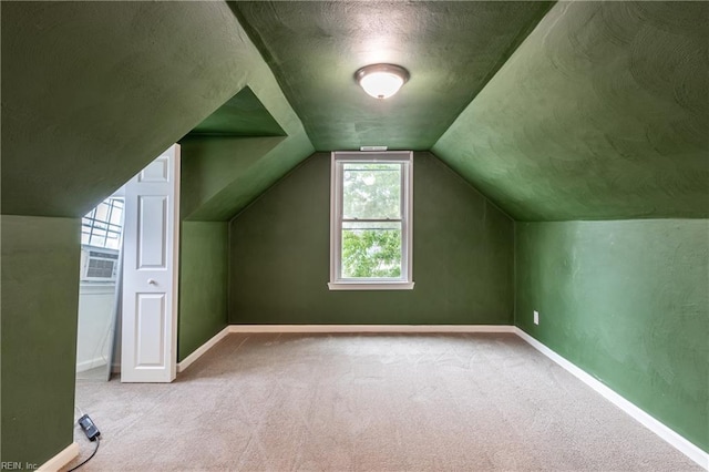 additional living space featuring cooling unit, a textured ceiling, light carpet, and vaulted ceiling