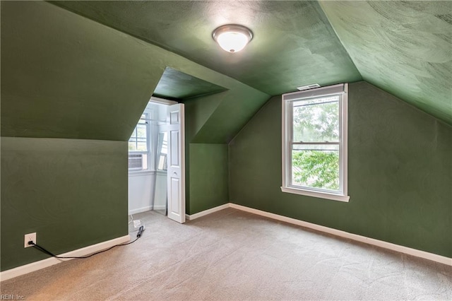 bonus room with light colored carpet and vaulted ceiling