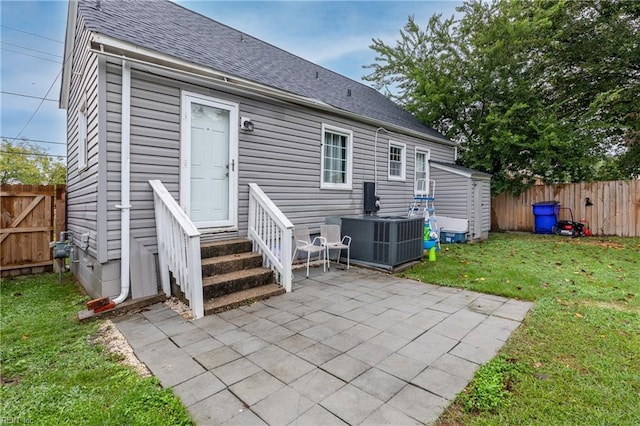 back of house with central air condition unit, cooling unit, a patio area, and a lawn