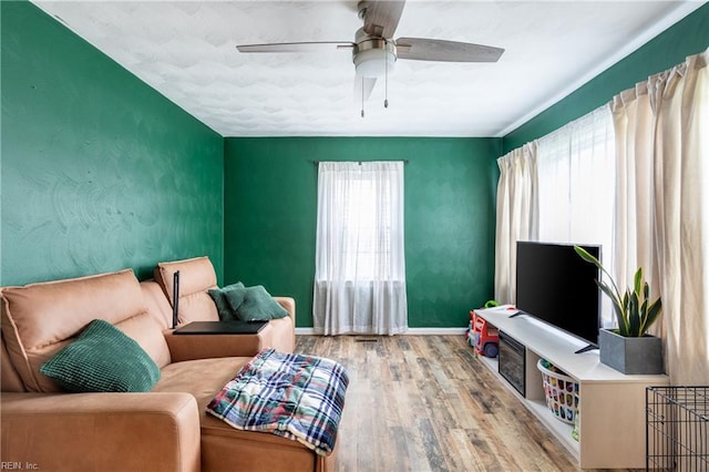 living area with ceiling fan and light hardwood / wood-style flooring