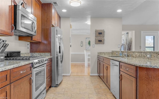 kitchen with sink, light stone counters, and appliances with stainless steel finishes