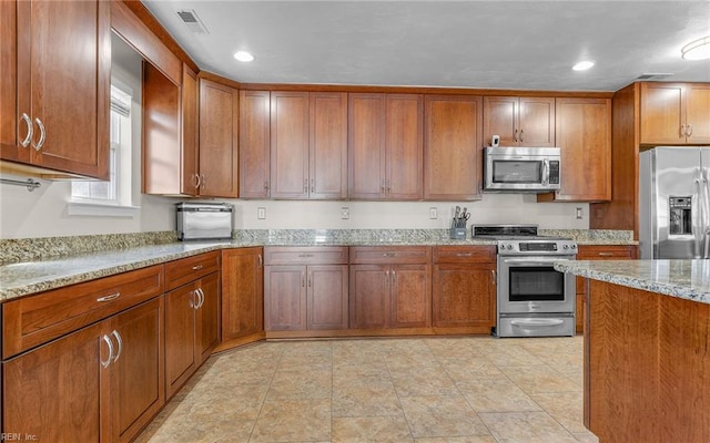 kitchen featuring appliances with stainless steel finishes and light stone counters