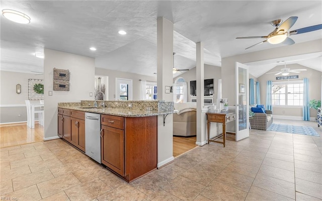 kitchen with light stone counters, kitchen peninsula, vaulted ceiling, and sink