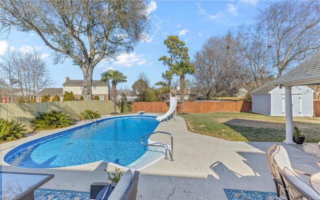 view of swimming pool with a water slide, a yard, a storage unit, and a patio