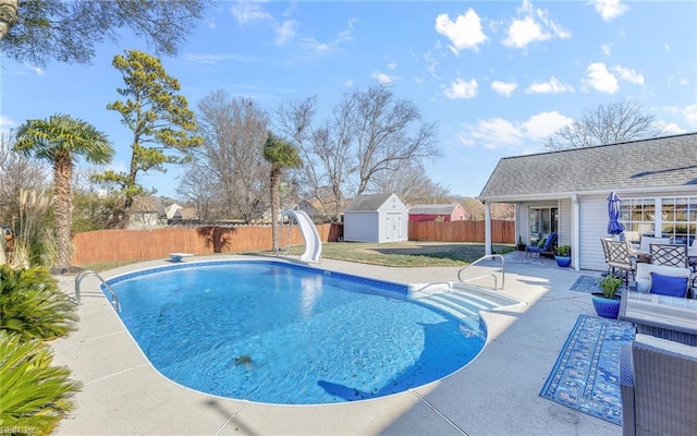 view of swimming pool with a patio area, a water slide, a diving board, and a storage unit