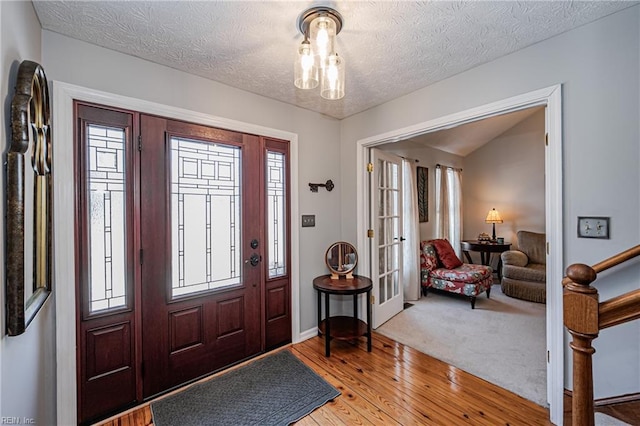 entryway featuring light wood-type flooring, french doors, a textured ceiling, and plenty of natural light