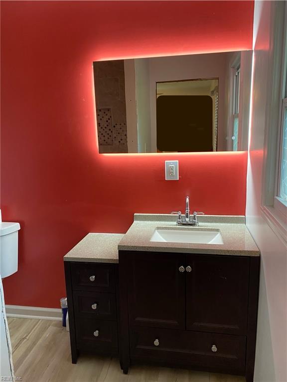 bathroom with toilet, vanity, and hardwood / wood-style flooring