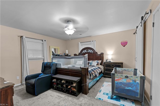 bedroom with ceiling fan, a barn door, and carpet flooring