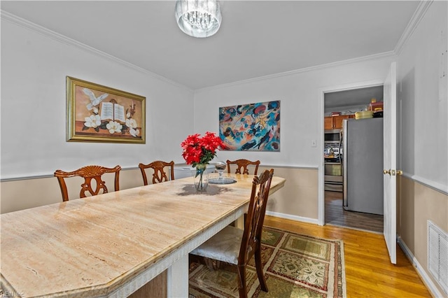 dining space featuring hardwood / wood-style flooring, a notable chandelier, and ornamental molding