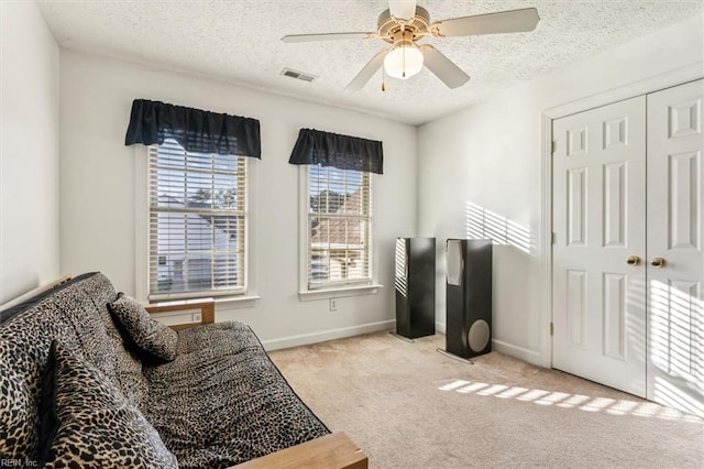 sitting room featuring light colored carpet, ceiling fan, and a textured ceiling