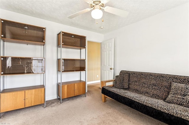 carpeted living room with ceiling fan and a textured ceiling