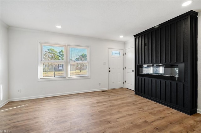 foyer entrance with light hardwood / wood-style floors and crown molding