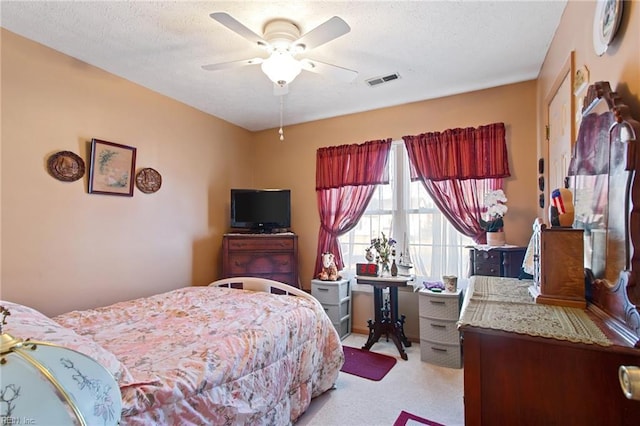 bedroom with ceiling fan, light carpet, and a textured ceiling