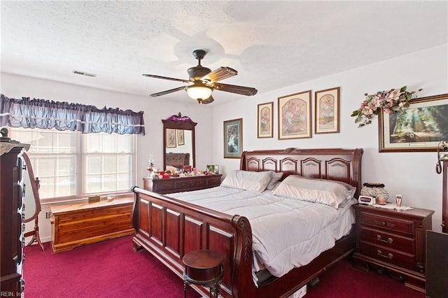 bedroom with a textured ceiling, ceiling fan, and dark colored carpet