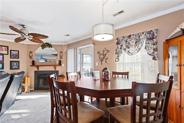 carpeted dining space with ceiling fan and crown molding