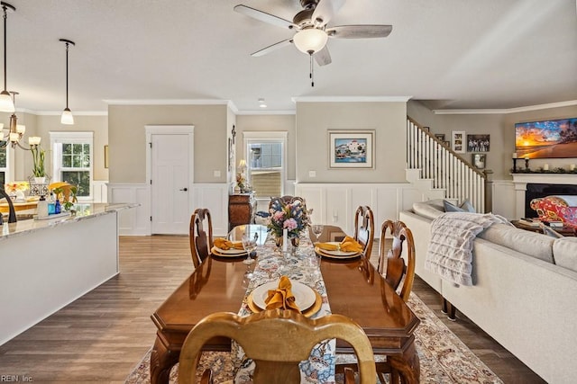 dining area with ceiling fan with notable chandelier, ornamental molding, and dark hardwood / wood-style floors