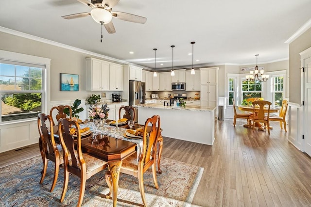 dining room featuring ornamental molding, light hardwood / wood-style flooring, a wealth of natural light, and ceiling fan with notable chandelier