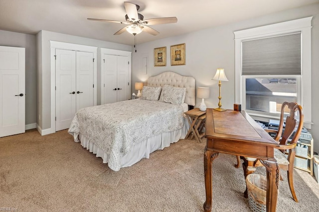 bedroom with ceiling fan, multiple closets, and light carpet