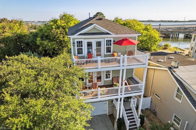 back of house with a balcony, a garage, and a water view