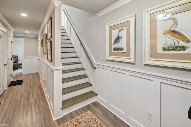 stairs with crown molding and wood-type flooring