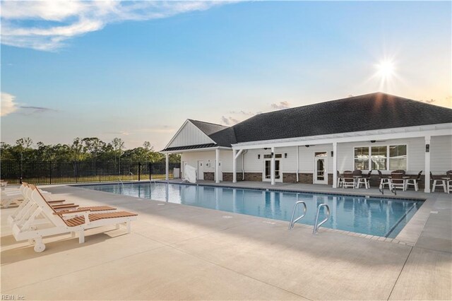 pool at dusk with ceiling fan, a patio, and french doors