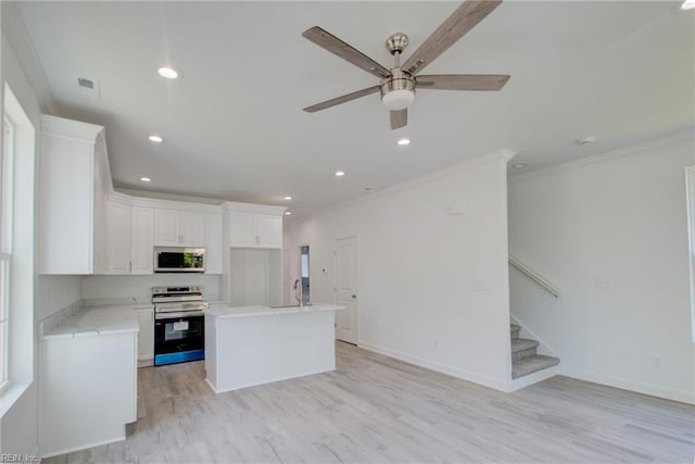 kitchen featuring ceiling fan, appliances with stainless steel finishes, white cabinets, and a center island