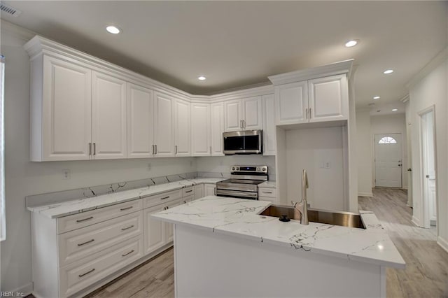 kitchen with stainless steel appliances, white cabinetry, light stone counters, and sink