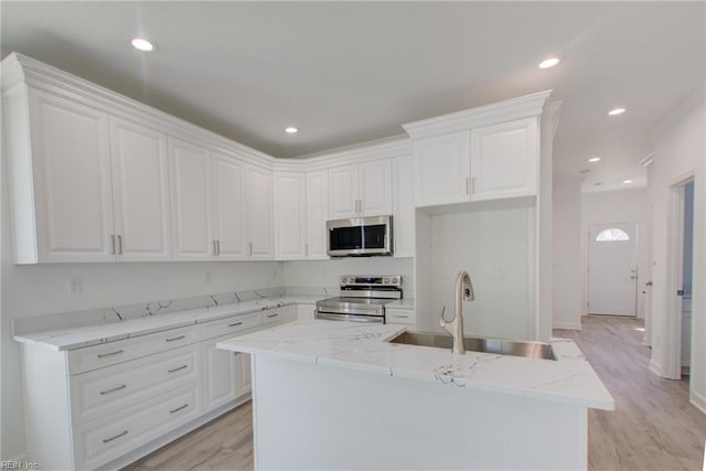 kitchen featuring appliances with stainless steel finishes, a kitchen island with sink, white cabinetry, and sink