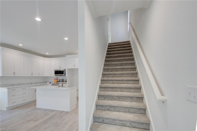 stairway featuring wood-type flooring and sink