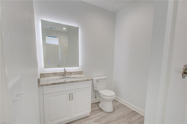 bathroom with toilet, hardwood / wood-style flooring, and vanity