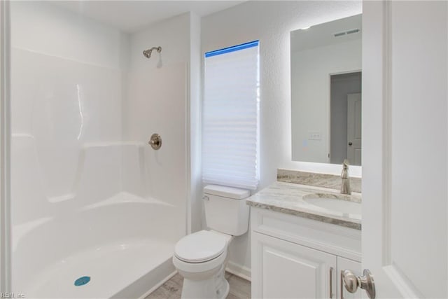 bathroom featuring toilet, vanity, and a shower