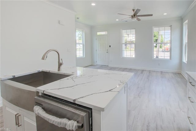 kitchen with white cabinetry, ceiling fan, light stone counters, stainless steel dishwasher, and light hardwood / wood-style flooring