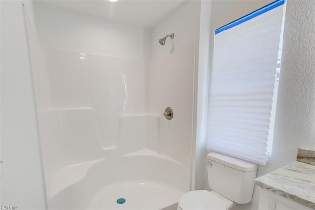 bathroom featuring toilet, a wealth of natural light, a shower, and vanity