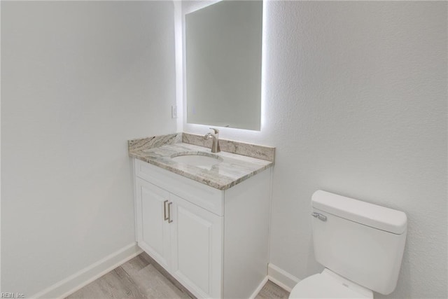 bathroom featuring toilet, vanity, and hardwood / wood-style floors