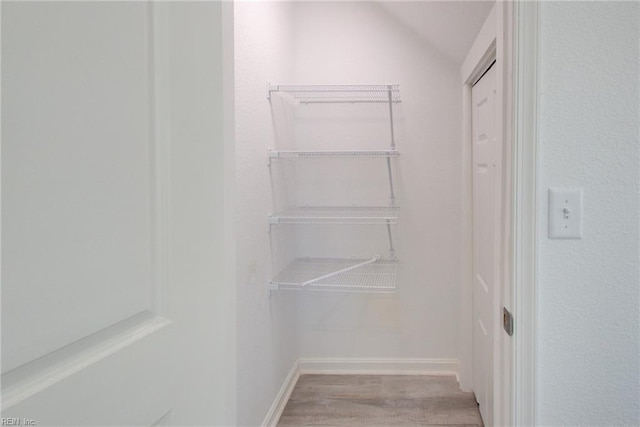 spacious closet featuring lofted ceiling and light hardwood / wood-style flooring