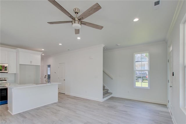 kitchen with white cabinetry, an island with sink, ceiling fan, stainless steel appliances, and light hardwood / wood-style flooring