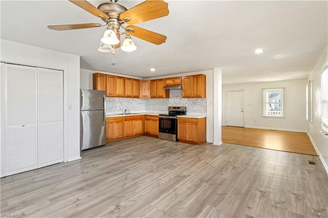 kitchen featuring stainless steel appliances, sink, ceiling fan, light hardwood / wood-style floors, and tasteful backsplash