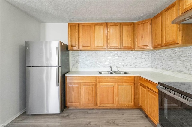 kitchen featuring sink, stainless steel fridge, light wood-type flooring, and decorative backsplash