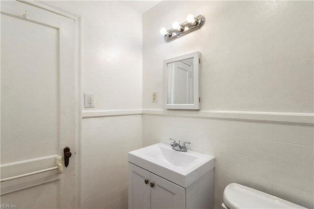 bathroom featuring tile walls, vanity, and toilet