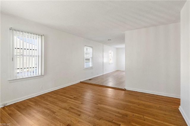 spare room with hardwood / wood-style floors and plenty of natural light