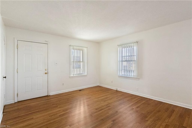 spare room featuring plenty of natural light and hardwood / wood-style flooring