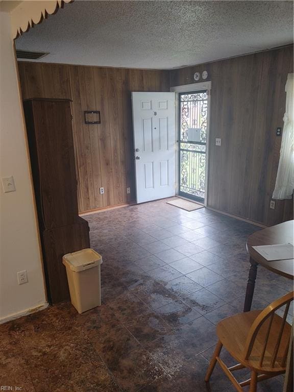 foyer entrance featuring a textured ceiling and wood walls