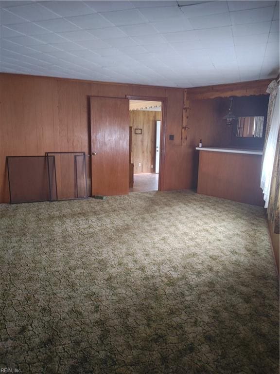 carpeted spare room with wooden walls