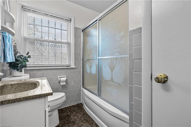 full bathroom with tile patterned flooring, tile walls, toilet, bath / shower combo with glass door, and vanity