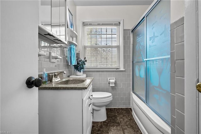 full bathroom with vanity, toilet, shower / bath combination with glass door, and tile walls