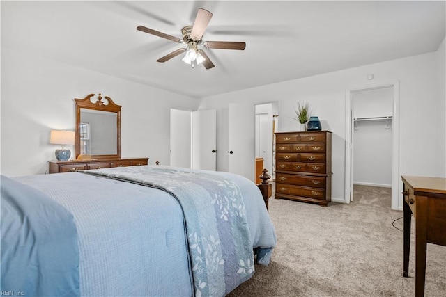 bedroom with a walk in closet, light carpet, a closet, and ceiling fan