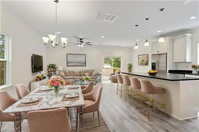 dining room with light wood-type flooring and ceiling fan with notable chandelier