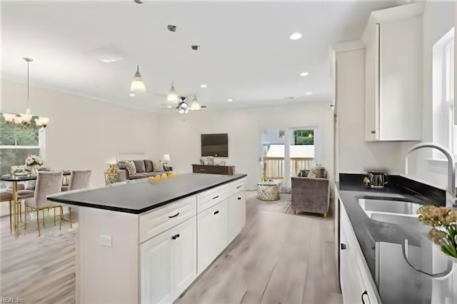 kitchen with light hardwood / wood-style floors, a center island, pendant lighting, sink, and white cabinetry